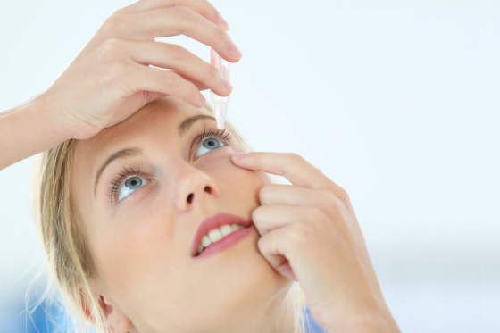 woman placing eye drops in her eye to cure dry eye